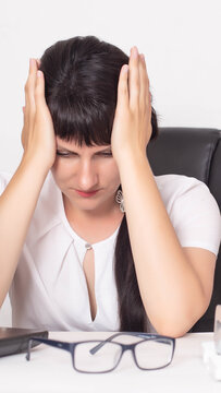 Businesswoman suffering from severe headache or burnout at workplace, hands holding head, eyes closed, expressing emotional distress and mental fatigue, vertical photo