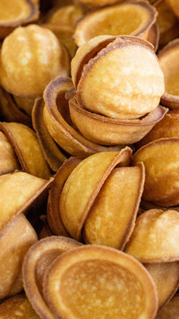 Close-up of numerous golden-baked shell-shaped cookies, traditional sweet dessert treats for celebration, rich texture and warm color, delicious snack food, vertical photo