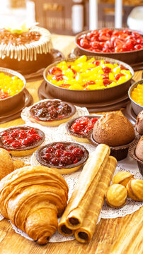 Display of diverse baked goods and pastries including fruit tarts, croissants, muffins, waffle rolls, and cake on wooden table in bakery setting with warm light vertical photo