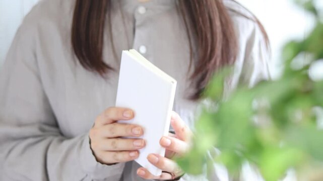 本を読む人　栞紐を挟んで本を閉じる様子