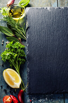 Culinary Herbs Spices and Olive Oil with Slate Board Background and Copy Space
