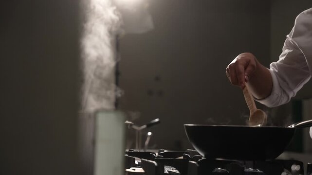Professional chef preparing a meal by saut&eacute;ing ingredients in a pan over a flaming gas stove