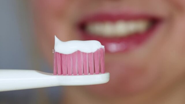 Close-up of pink toothbrush with white toothpaste ready for brushing teeth