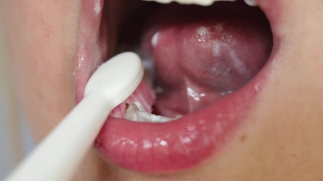 Close-up of person brushing their tongue with a toothbrush for oral hygiene