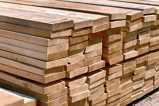 Large stack of freshly cut wooden lumber boards stored outdoors. Construction materials for building, carpentry, woodworking and timber industry.