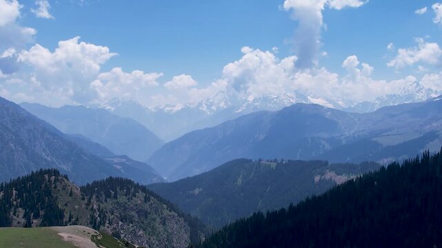 Forested ridges frame a broad mountain valley beneath Hindu Kush peaks near Kalam, Khyber Pakhtunkhwa, Pakistan