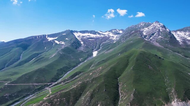 Green ridges lead to snowcapped Hindu Kush peaks at Badgoi Pass, Kalam, Pakistan
