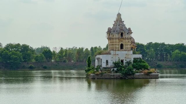 Static shot of the historic Shiva Temple standing on a small island surrounded by the calm waters of Rani Talab in Rewa Madhya Pradesh
