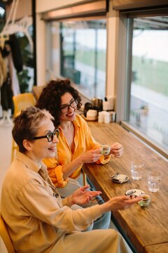 Generational women friends enjoying coffee, conversation in cafe