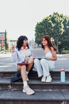 two young latin university women students using laptop sitting on bench park outdoors in Mexico Latin America, hispanic girls studying 