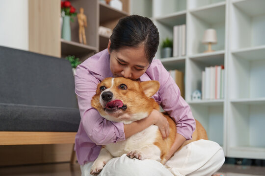 Asian woman hugging her happy corgi dog at home for pet companionship