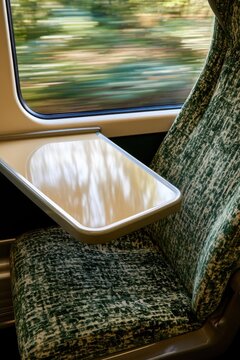 Green patterned train seat with tray table and window view