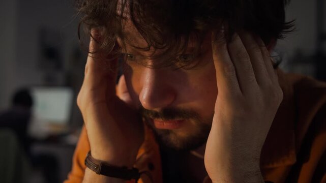 Caucasian young adult male office worker massaging temples due to headache while working late. Ideal for corporate wellness, mental health awareness, and pain relief ads