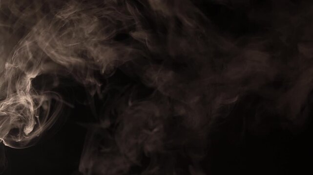 Wisps of smoke gracefully swirl and dance against a dark background