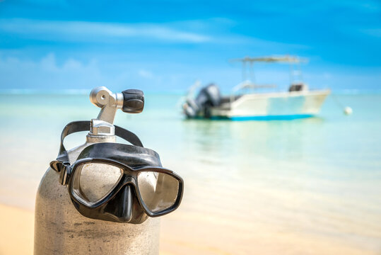 Scuba diving gear on display at pristine tropical beach diving holiday destination of Moorea, French Polynesia, with diving boat in the background, dive tank and masks, on sunny day with blue skies