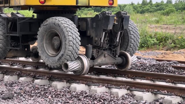 Close-up of special flanged steel wheels of a hi-rail excavator on railway tracks. Railway transport, track maintenance, heavy machinery.
