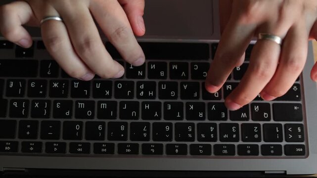 Close-up of hands typing on a laptop keyboard with a silver ring