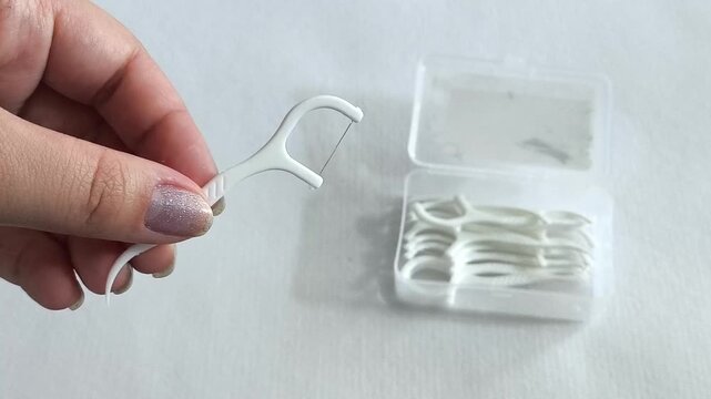 floss pick in the hand, daily oral hygiene, plaque removal and preventive dental care.