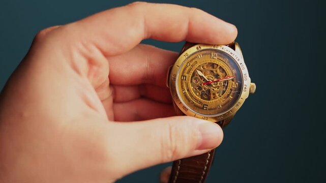 Close-up of a hand holding a vintage mechanical wristwatch with intricate details
