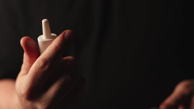 Close-up of hand holding a nasal spray bottle for medication administration