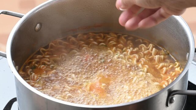 Putting Tteokbokki (rice cake) into a pot of boiling spicy instant noodles soup