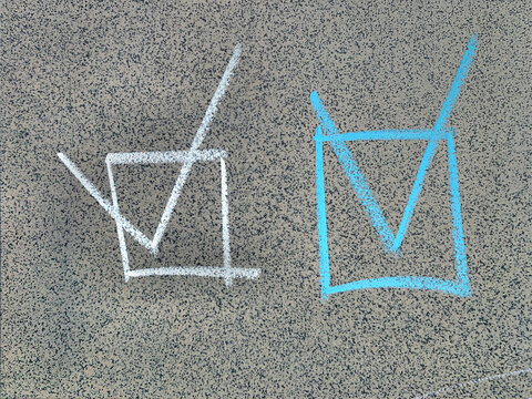 Handwritten white and blue checkmark symbols inside square boxes in chalk on a grey stone wall, business and checklist concept.