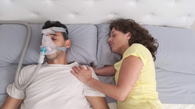 Man sleeping with CPAP mask beside partner in bed