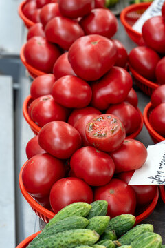 Ripe red tomatoes on a market stall. Tomatoes for sale at a market. A cut tomato reveals its ripe, juicy flesh and texture.