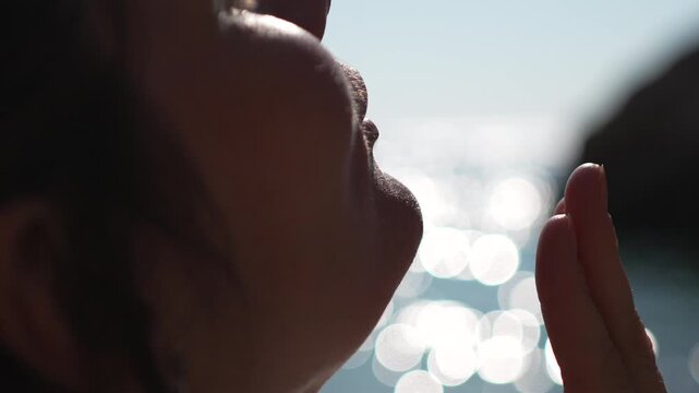 Woman skincare beach profile of a beautiful young female applying refreshing water to her face while relaxing outdoors during summer