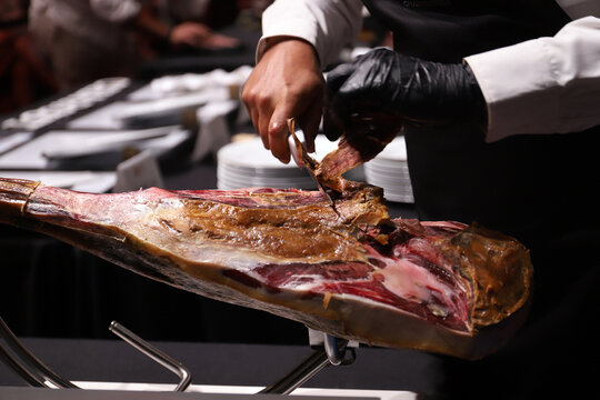 maestro cortador jamonero limpiando y cortando el tocino y la capa de un jam&oacute;n ib&eacute;rico 
