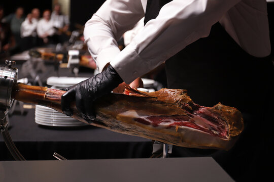 experto cortador de jam&oacute;n manipulando un jam&oacute;n y limpi&aacute;ndole de tocino
