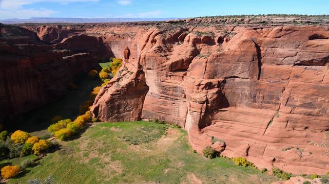 Spectacular red sandstone cliffs and the vibrant green canyon floor of Canyon de Chelly National Monument in Arizona, USA.
