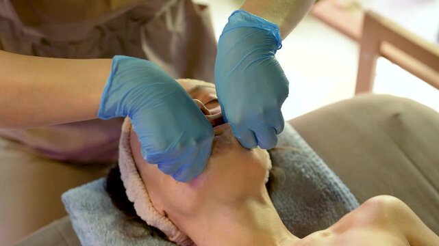 Professional therapist performing buccal facial massage wearing disposable gloves. Intraoral sculpting technique from facial muscle tension, improve jawline definition, support lymphatic drainage.