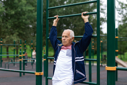 Old man doing exercises on vertical ladder outdoors