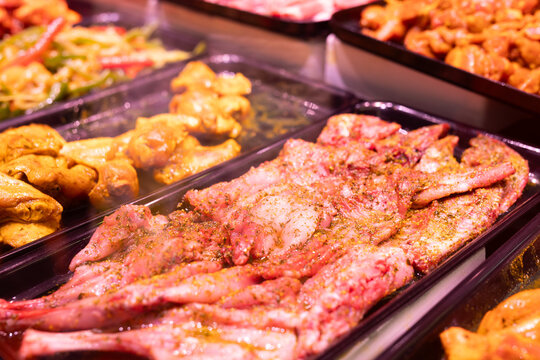 Raw skinned marinated rabbit quarters and halves in refrigerator cabinet of butcher shop
