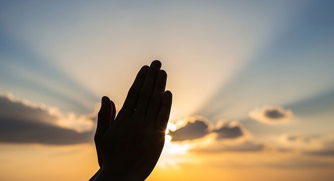 Hand reaching for sun at sunset.
