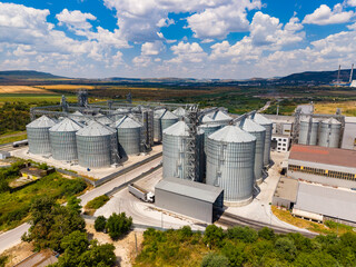 Storage silos are located near a field with clouds in the sky during the daytime in a rural setting © DSMT