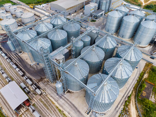Industrial site with multiple storage silos and nearby train tracks during daylight hours © DSMT