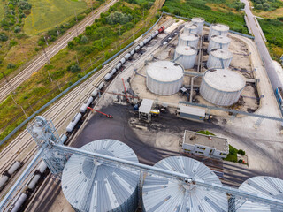 Elevated view of a storage facility with silos and railcars at a location near agricultural fields during the daytime © DSMT