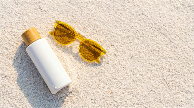 Sunscreen bottle and sunglasses on sand. Summer skincare products for beach vacation.