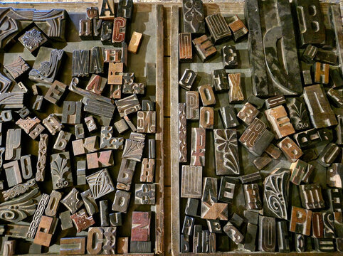Antique wooden letterpress printing blocks scattered in a vintage wooden tray