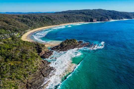 Aerial view of Sugarloaf Point and Boat Beach surrounded by crystal-clear turquoise water at Seal Rocks, NSW, Australia, showcasing the rugged coastline and pristine beauty of this destination