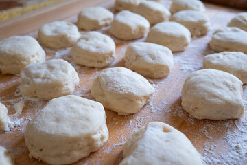 Fototapeta premium Wide angle perspective view of flour dusted raw dough portions arranged in rows on a wooden pastry board.