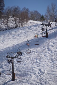 雪の斜面を登るスキーリフトと冬のスキー場を捉えたクリアな風景  
Clear winter scene featuring a ski lift ascending a snowy slope with riders
