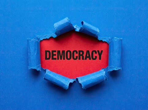 Democracy text, ripped blue paper revealing red background with word democracy, political concept