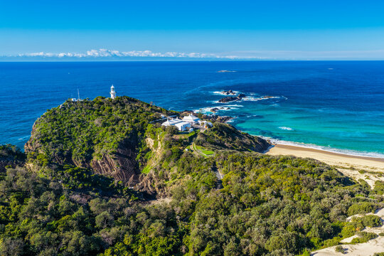 Aerial view of Lighthouse Beach leading towards the historic Seal Rocks Lighthouse, showcasing golden sand, rugged coastline and the clear blue waters of the Pacific Ocean at Seal Rocks, NSW