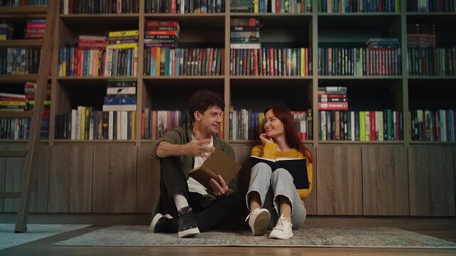 Young romantic couple discussing a book while sitting on library floor