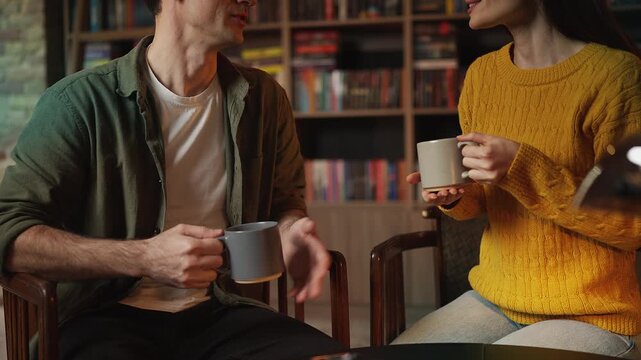 Smiling young couple talking over tea during romantic date in a library cafe