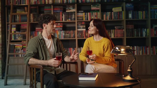 Cheerful young couple drinking wine and talking during romantic cafe date