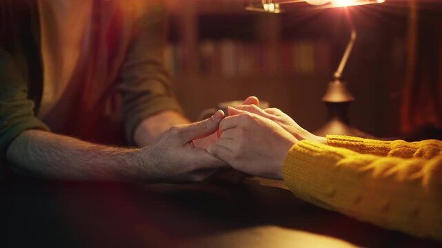 Close-up of young couple holding hands during romantic coffee shop date
